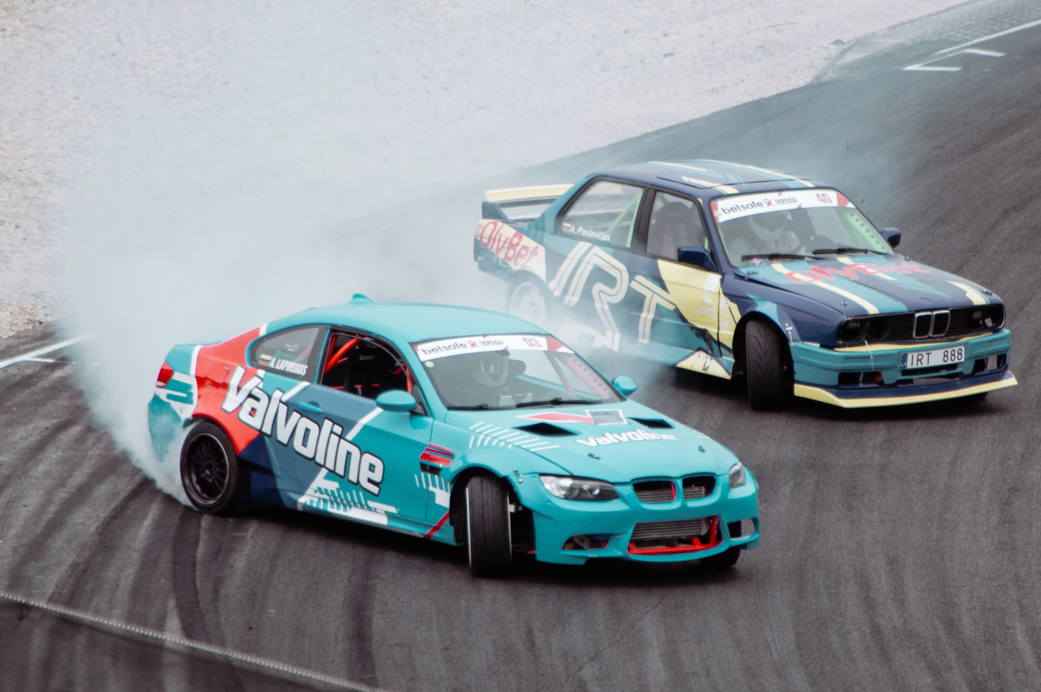 Two highly modified BMWs, an E92 and E30, drifting on track.